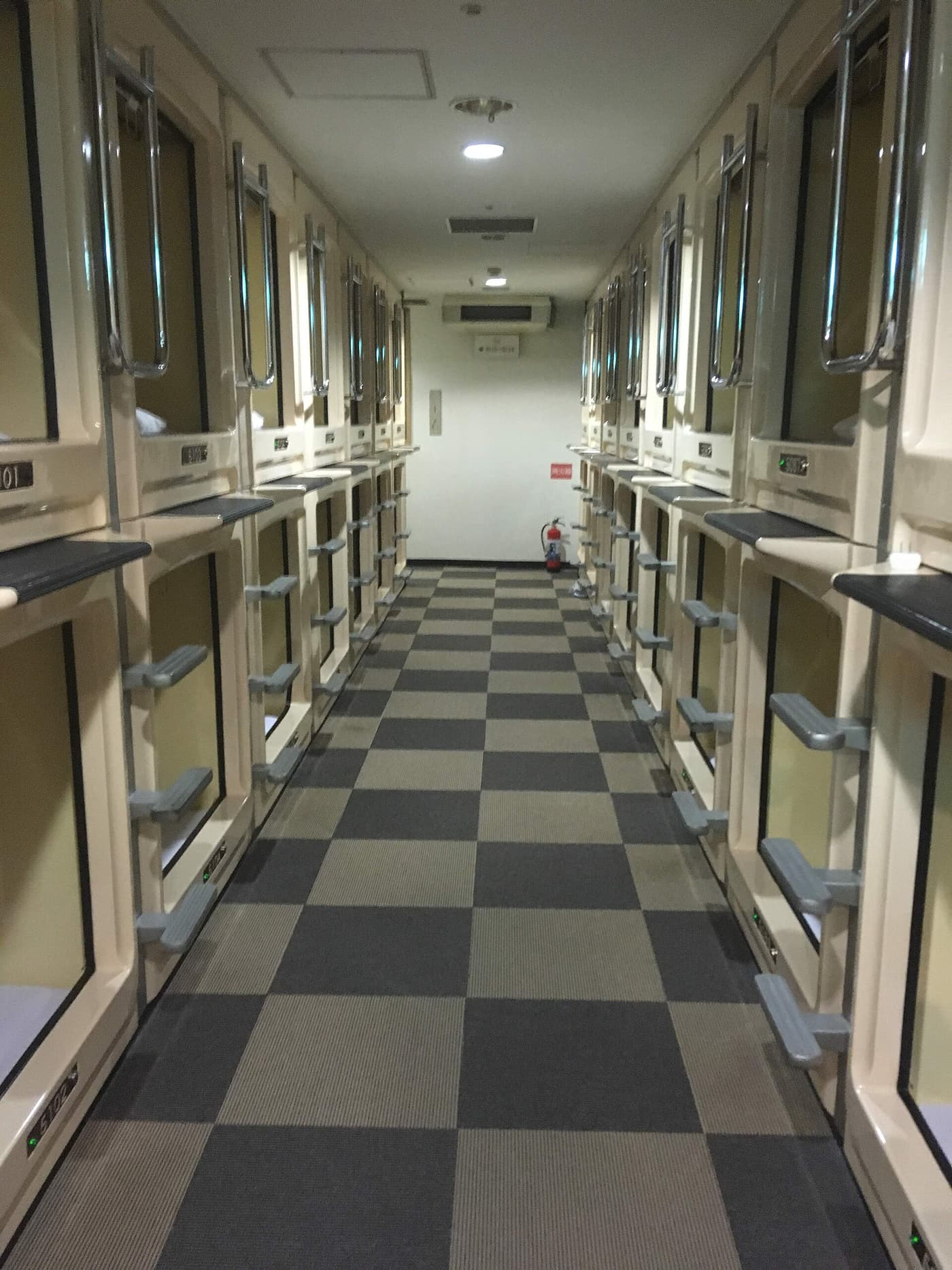 A corridor lined with capsule pods in a capsule hotel in Ueno