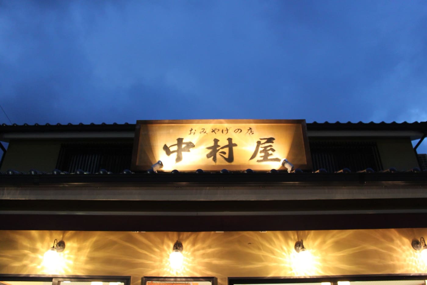 The lit wooden sign of a ryokan in Gora, Hakone, at dusk