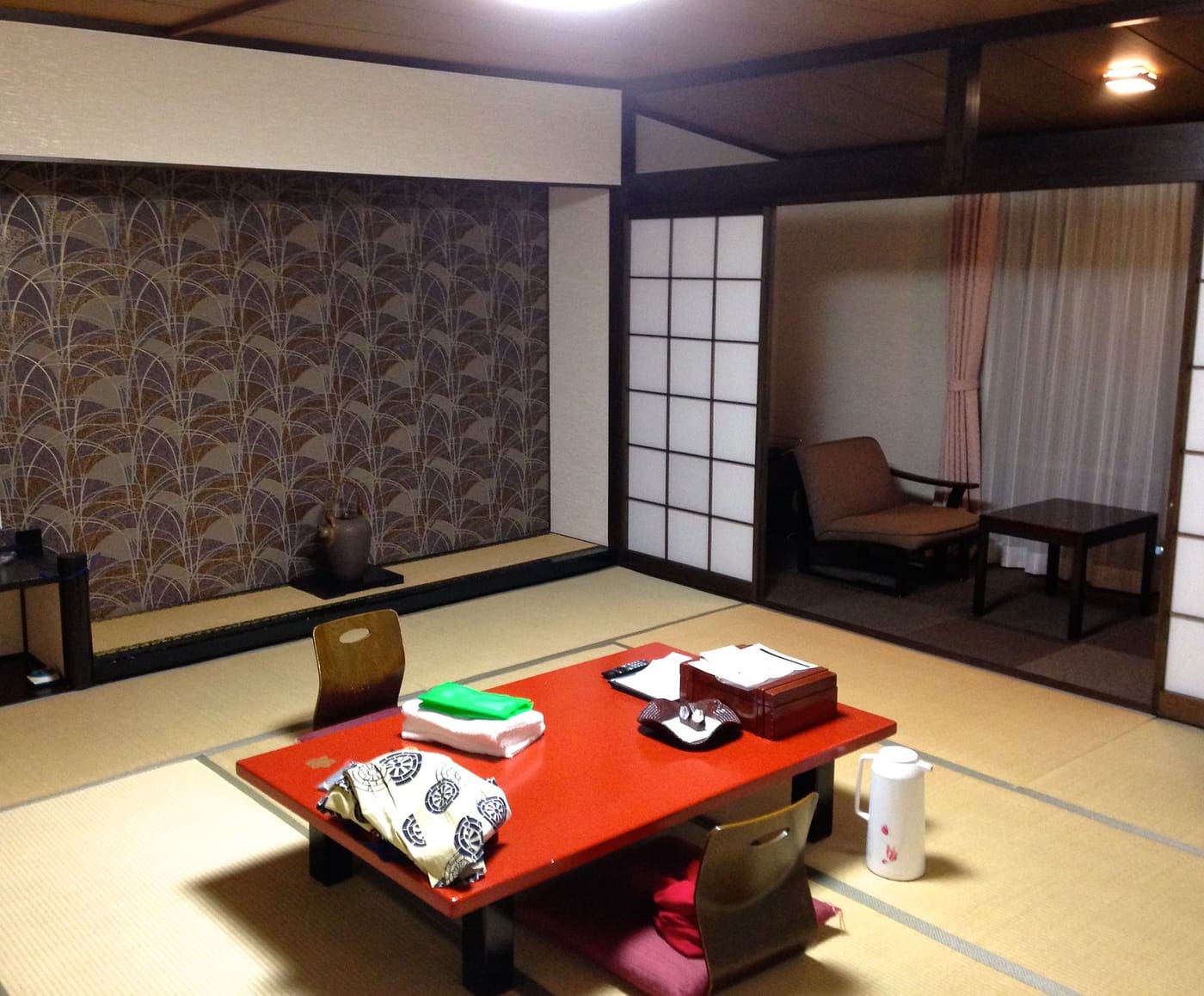 A tatami guest room with a low red table and shoji screens at a ryokan in Hakone