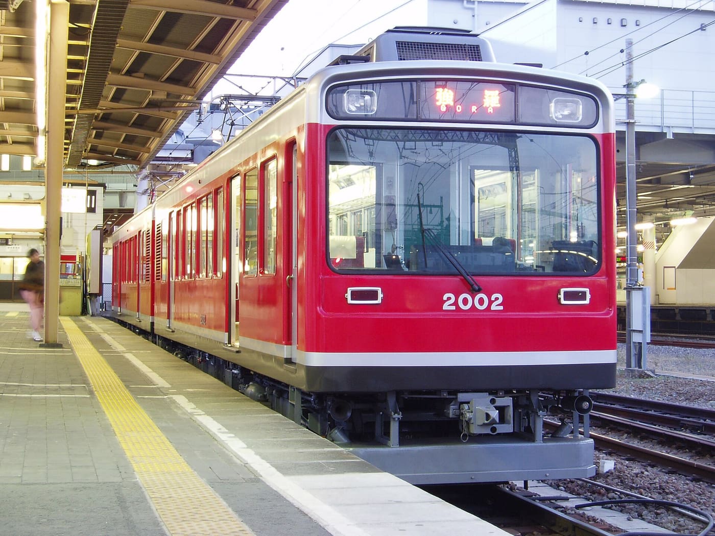 A red Hakone Tozan Railway train waiting at a station platform