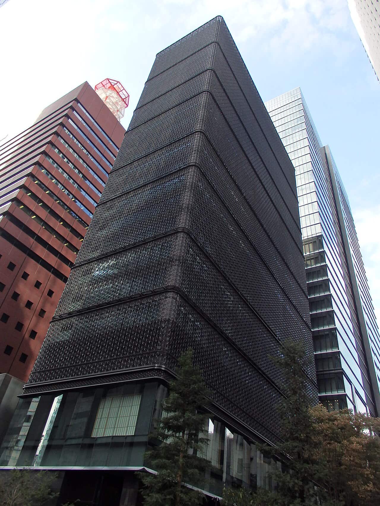 The dark lattice facade of Hoshinoya Tokyo among the office towers of Otemachi