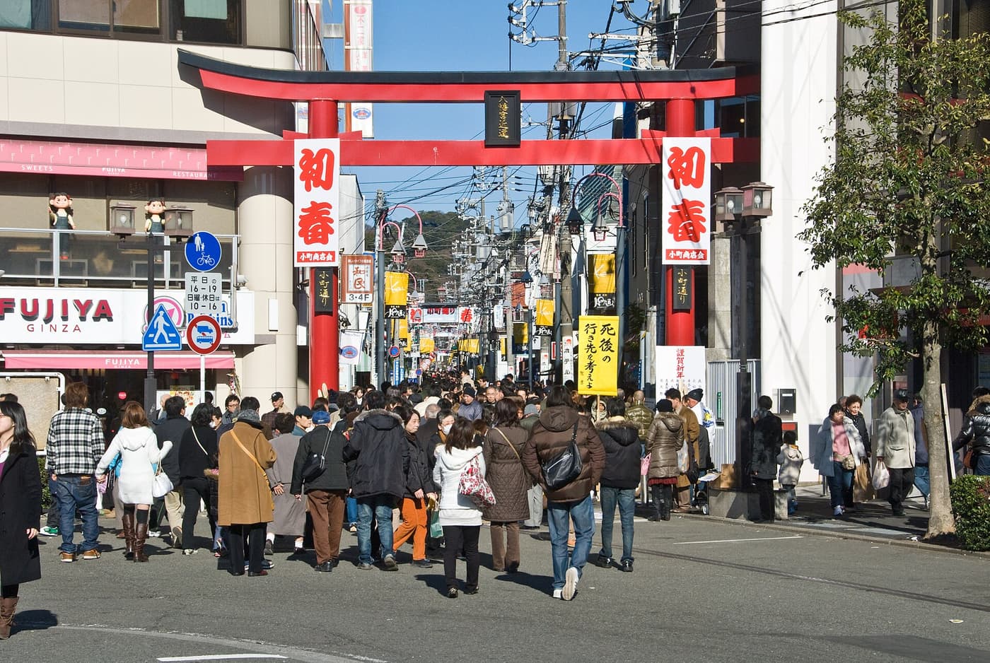Crowds entering Komachi-dori under its red torii gate beside Kamakura Station