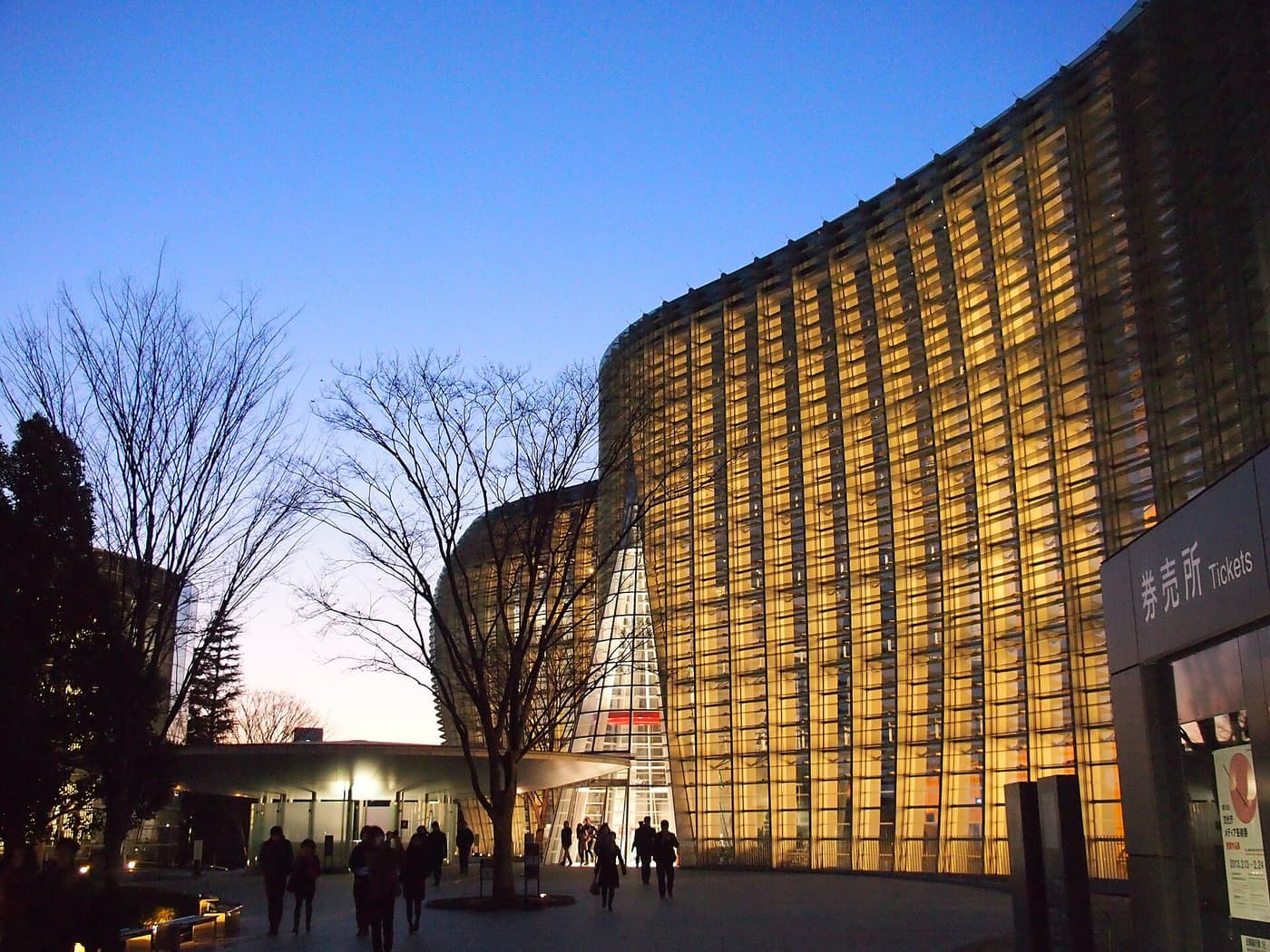 The glass facade of the National Art Center Tokyo glowing at dusk