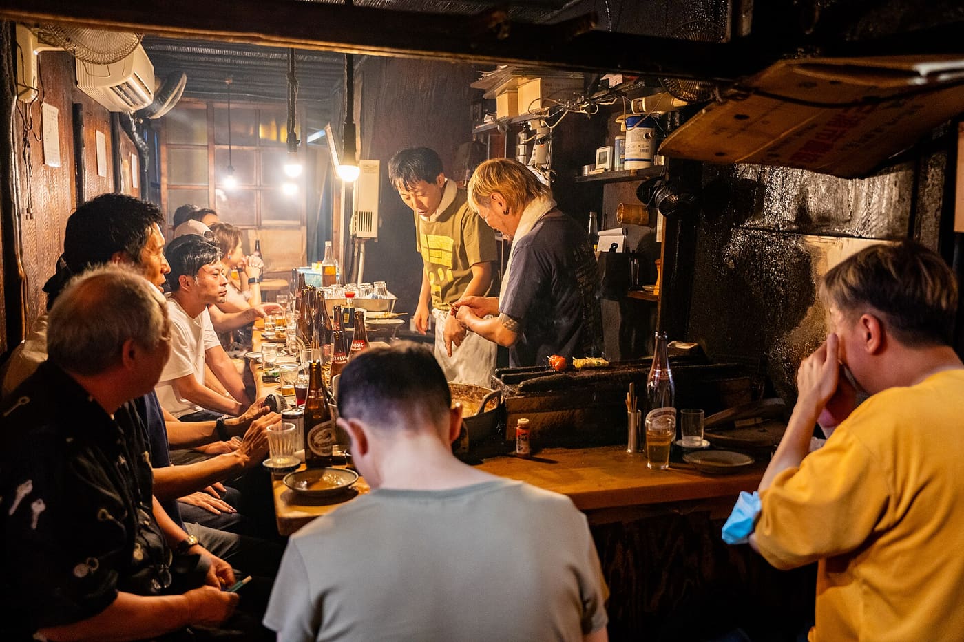 Diners at a smoky counter in the Omoide Yokocho alleys beside Shinjuku Station
