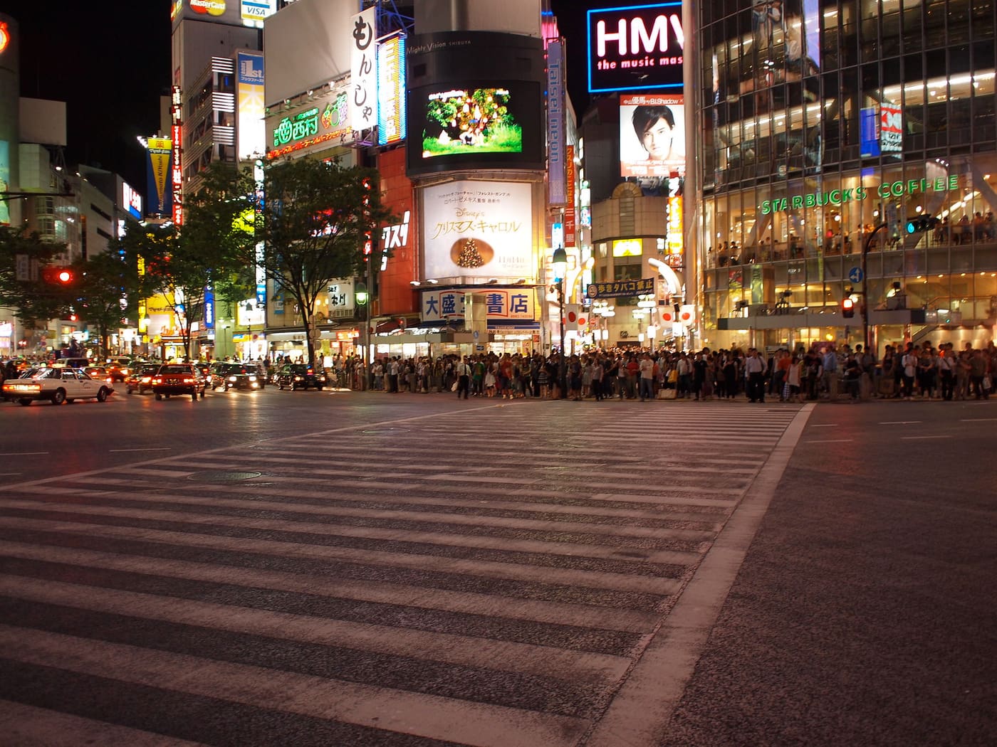 Le carrefour de Shibuya la nuit, sous les écrans et panneaux illuminés