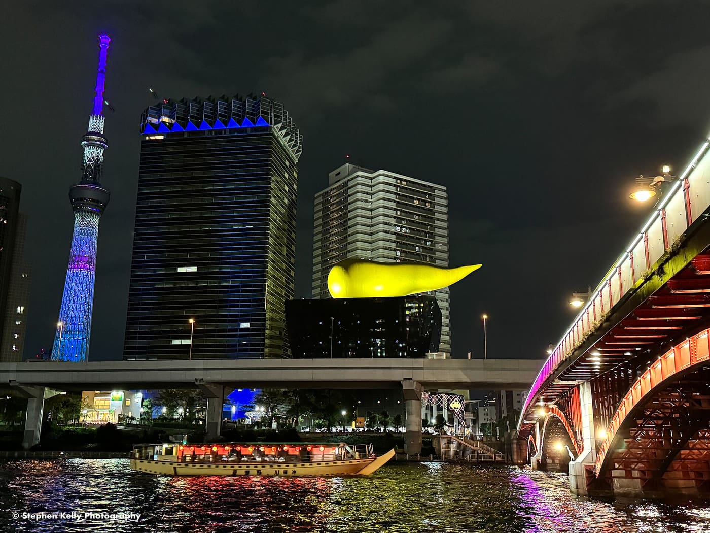 A tour boat on the Sumida River passing the riverside buildings of Asakusa