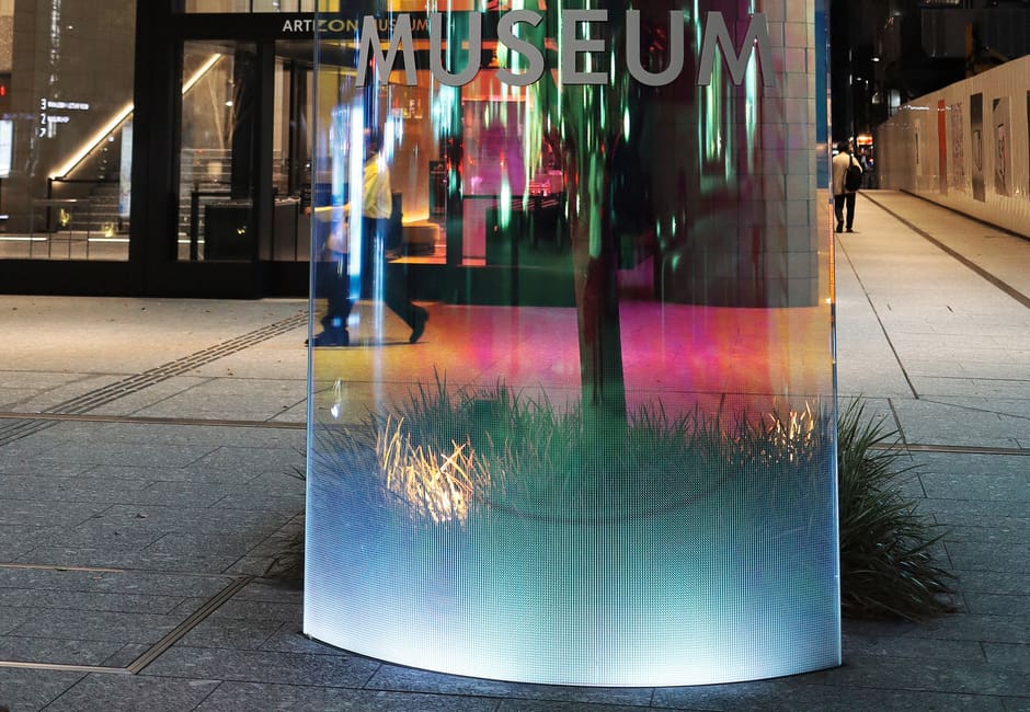 The lit glass sign of the Artizon Museum outside its entrance in Kyobashi at dusk