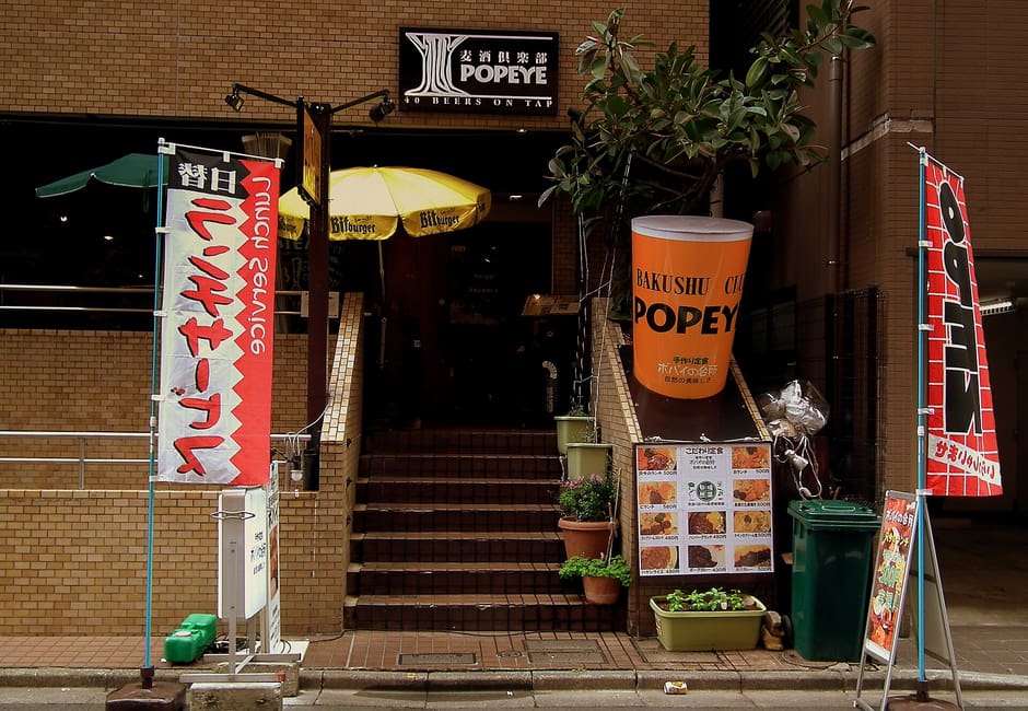 The entrance of Beer Club Popeye in Ryogoku, with its name sign and beer banners by the steps