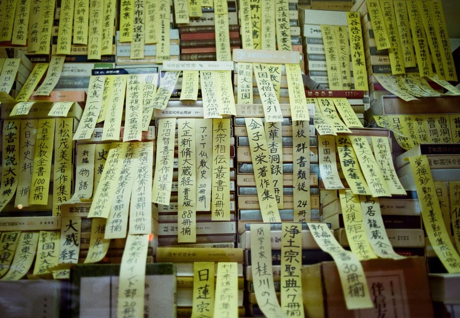 Stacks of secondhand books with handwritten title slips in a Jimbocho bookshop