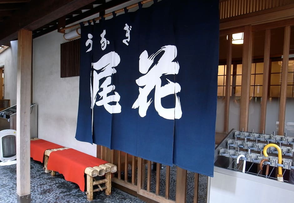 Navy noren printed with the Obana name at the unagi restaurant entrance in Minami-Senju