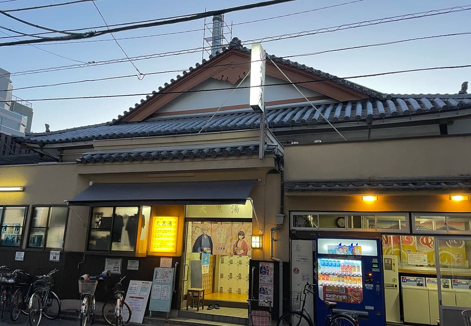 Tiled roofs and lit entrance of Oshiage Onsen Daikokuyu bathhouse at dusk in Yokokawa