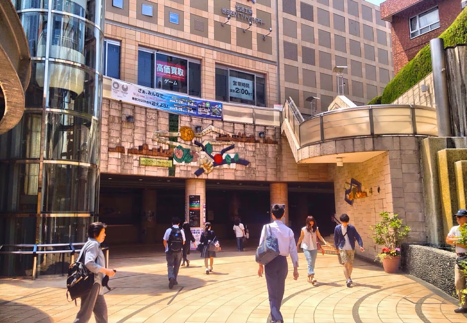 Plaza by Sangenjaya Station with shoppers below the Carrot Tower complex