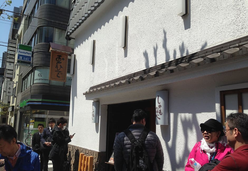 Diners queueing outside the white-walled entrance of Tamahide in Ningyocho