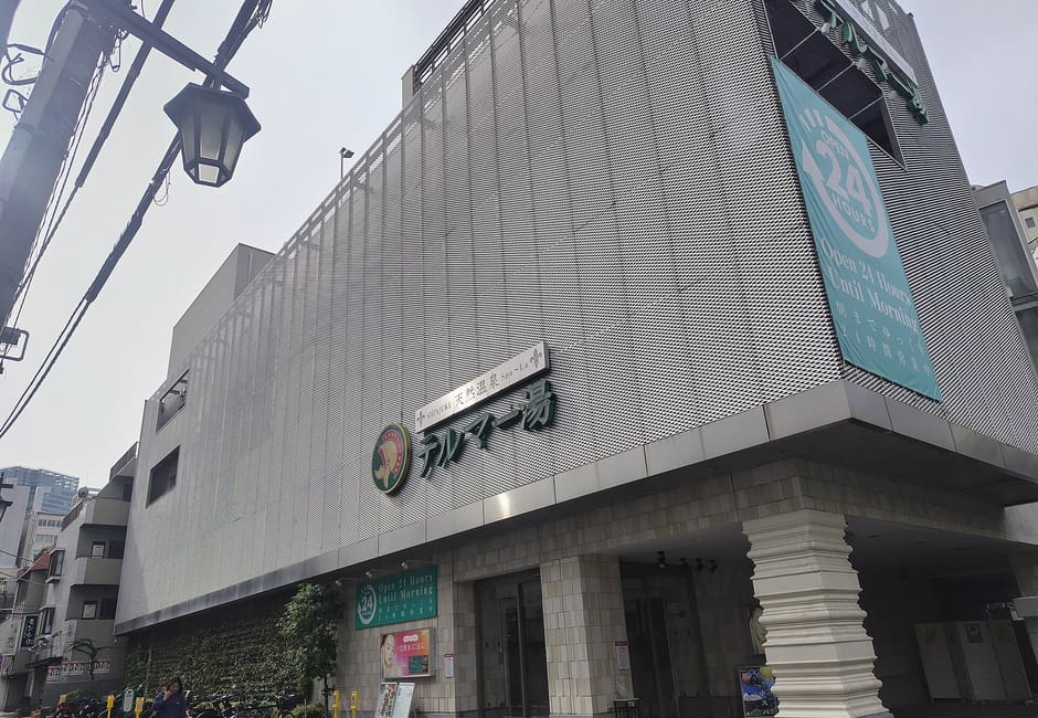 Grey Thermae-yu building with its name sign on a street corner in Kabukicho, Shinjuku