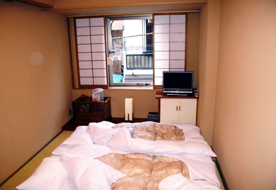 Futons étendus sur des tatamis sous des fenêtres shoji, dans une petite chambre de ryokan à Asakusa, Tokyo