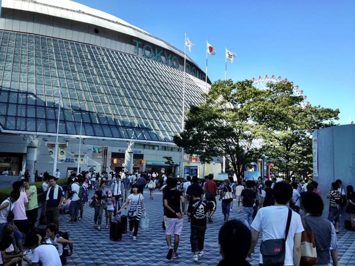 Tokyo Dome's curved glass facade and lettering above the approach at Suidobashi