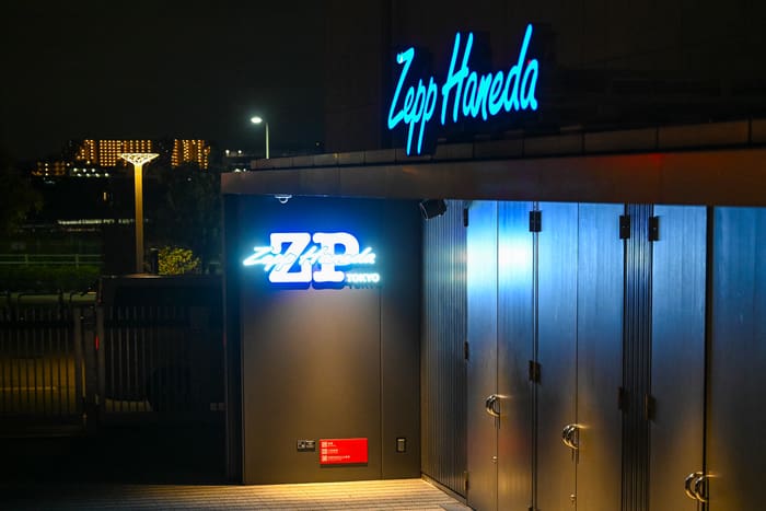 Blue neon Zepp Haneda sign above the hall's entrance at night by Haneda Airport